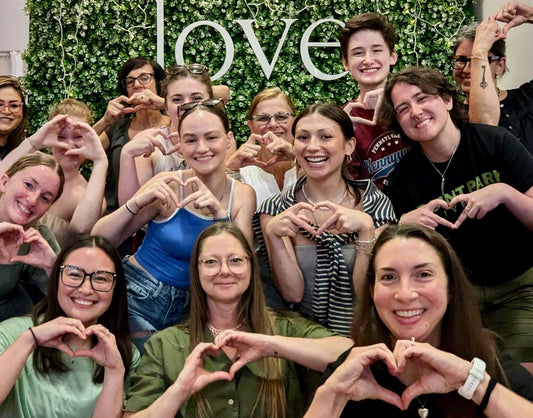 team members at love, store holding up heart hands
