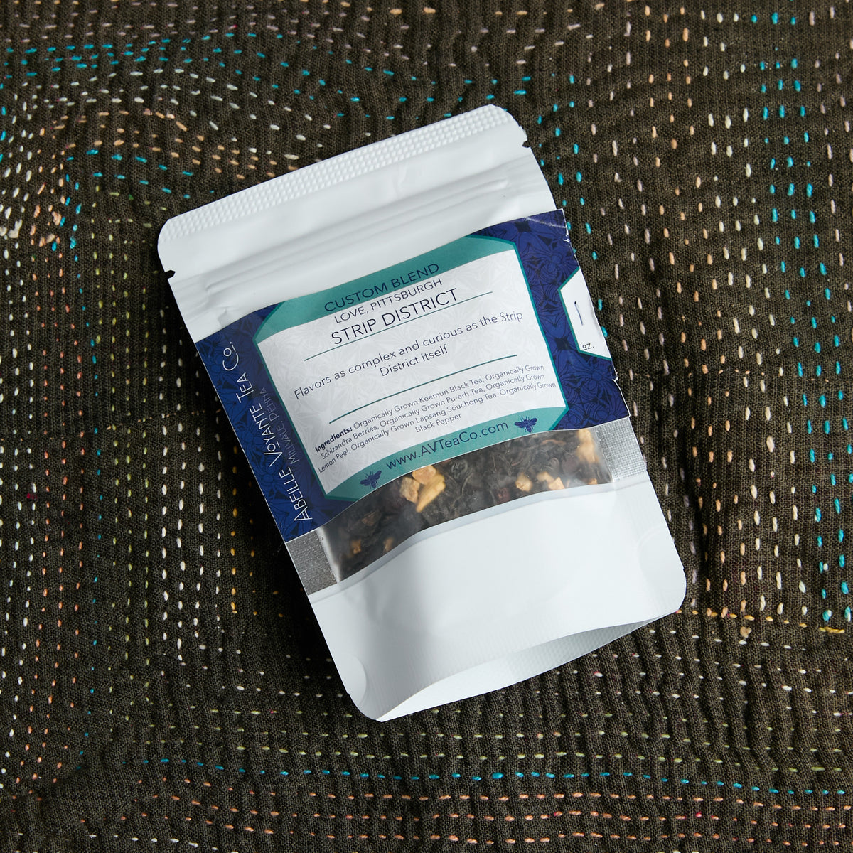 A stand-up pouch of ove, Pittsburgh Strip District tea from Abeille Voyante Co, placed on a textured brown woven blanket.