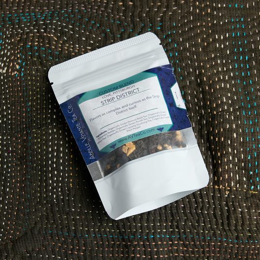 A stand-up pouch of ove, Pittsburgh Strip District tea from Abeille Voyante Co, placed on a textured brown woven blanket.