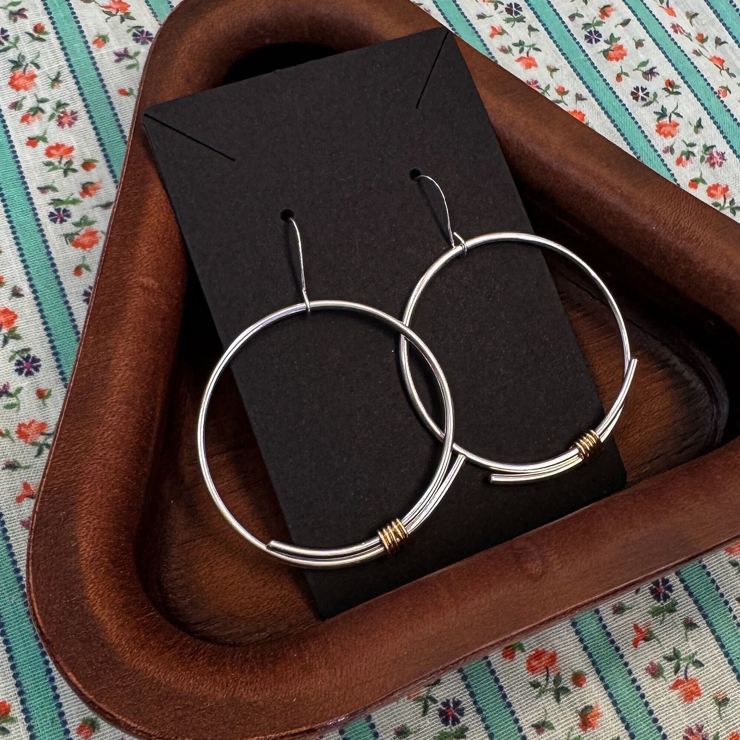 Jewelry set with hoop earrings and a black box on a floral-patterned surface