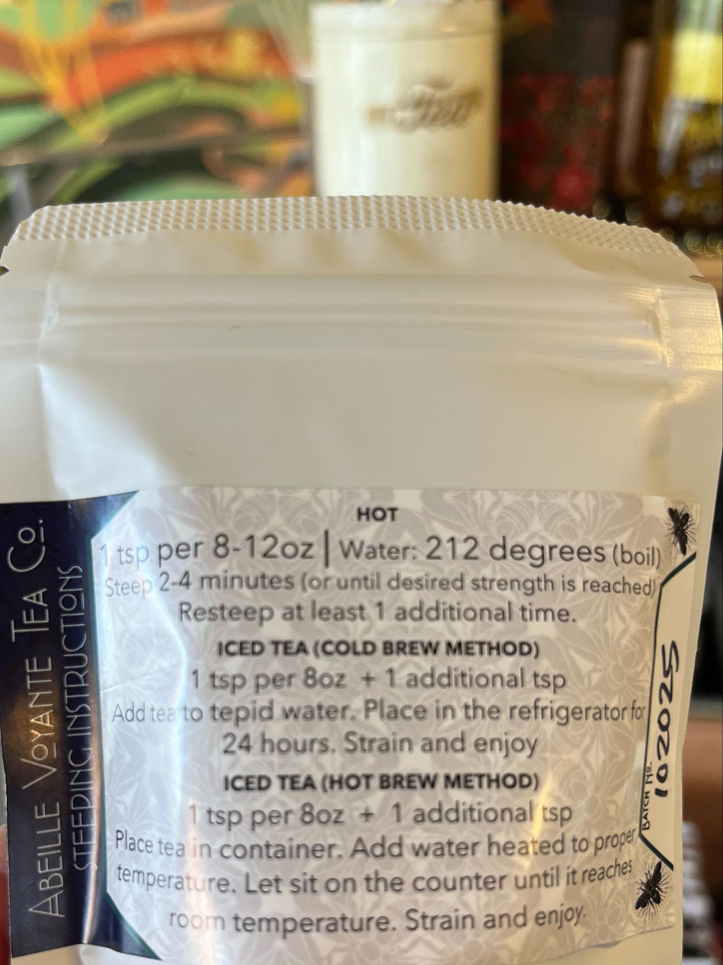 Tea package with brewing instructions held by a hand in a blurred indoor setting