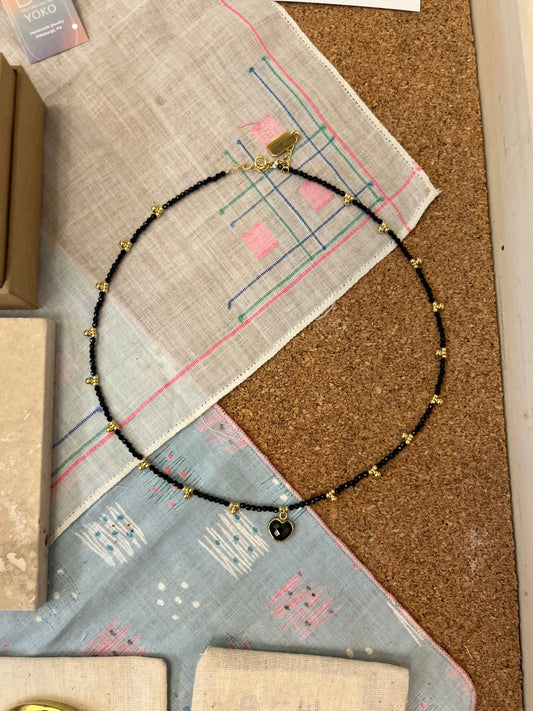 Black beaded necklace on a cork board with patterned paper underneath