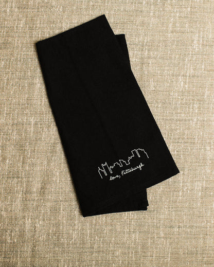 Black folded fabric with white text on a beige textured background