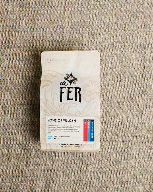 Coffee package labeled 'de Fer' on a textured beige fabric background