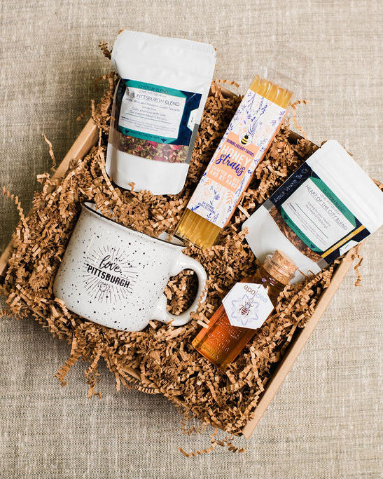 Gift basket with a mug, bottles, and other items on a textured surface