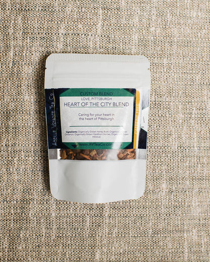 Tea package labeled 'Heart of the City Blend' on a textured beige fabric background