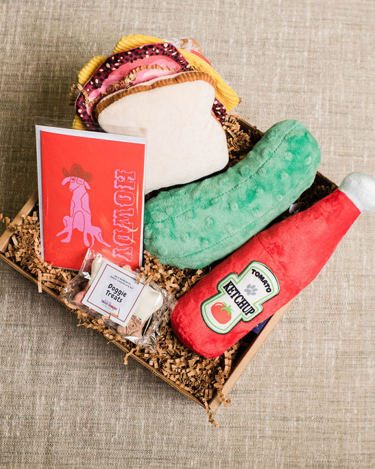 Plush toy set resembling a burger, pickle, and ketchup bottle on a textured surface