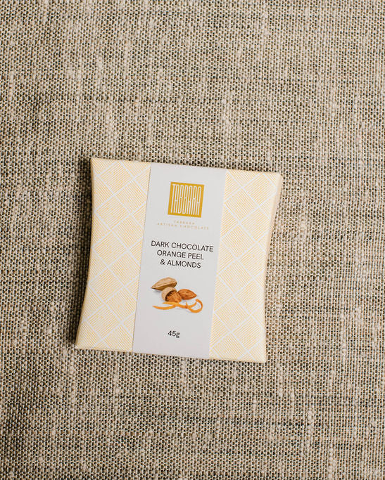 Bar of dark chocolate with almonds on a textured fabric background