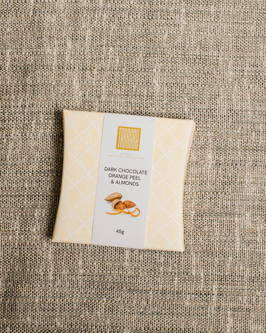 Bar of dark chocolate with almonds on a textured fabric background