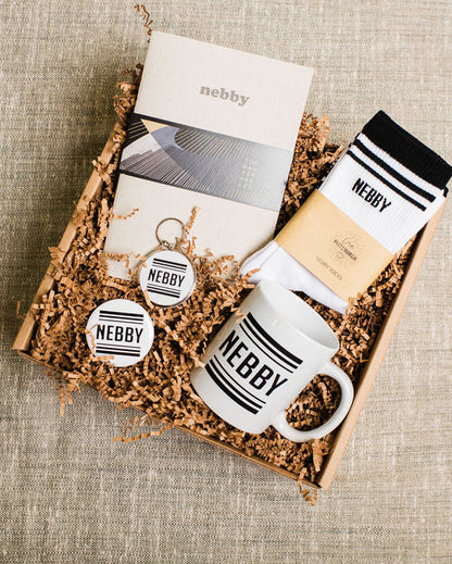Gift set with mug, keychain, and socks branded 'Nebby' on a textured surface.