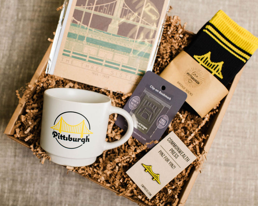 Gift box with bridge themed mug, socks, and cards on a textured surface