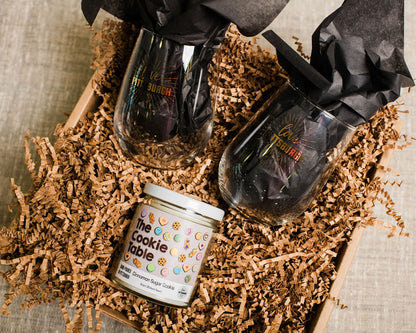 Candle and wine glasses on a textured surface with decorative paper