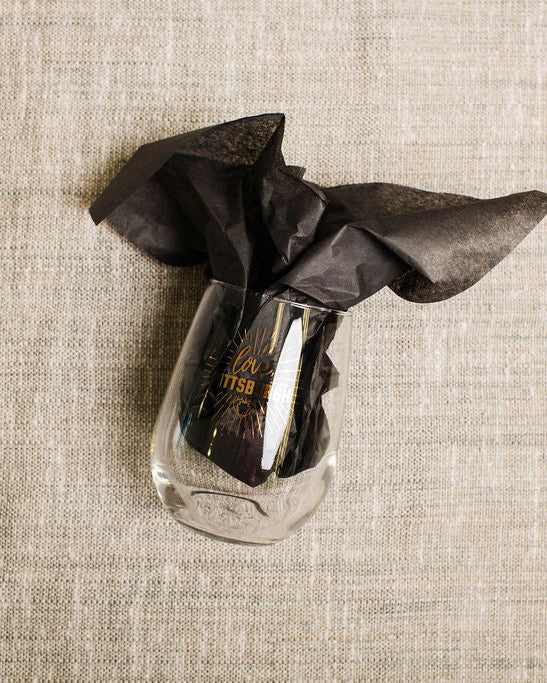 Clear wine  glass with a black cloth on a beige textured surface