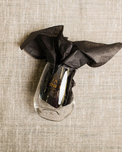 Clear wine  glass with a black cloth on a beige textured surface