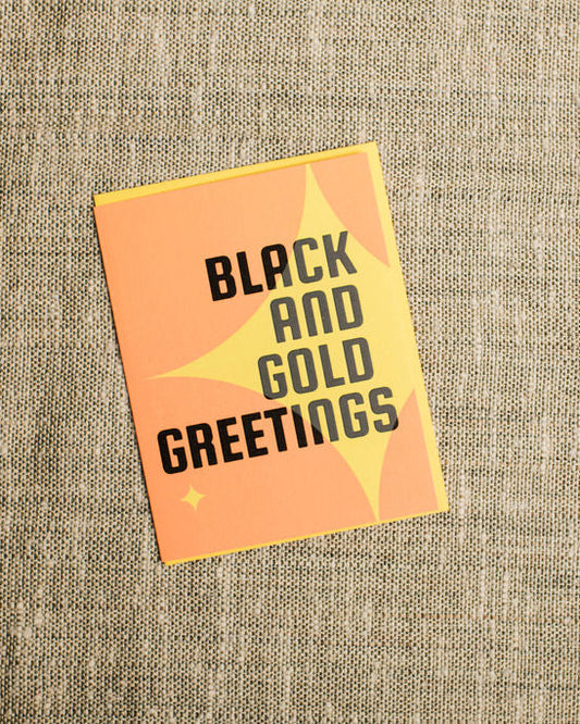 Greeting card with 'Black and Gold Greetings' text on a textured beige background