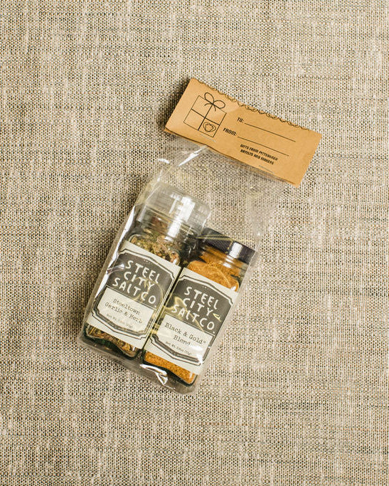 Two salts packaged with gift label  on a textured beige surface 