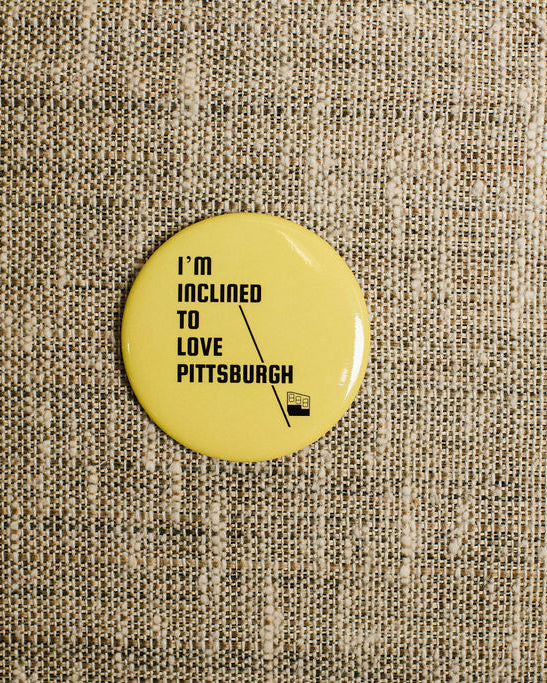 Yellow button with text 'I'm inclined to love Pittsburgh' on a textured beige background
