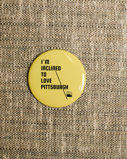 Yellow button with text 'I'm inclined to love Pittsburgh' on a textured beige background