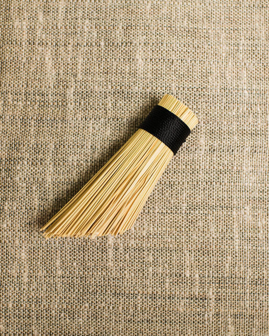 Wooden brush pot scrubber with black band on a textured beige fabric background
