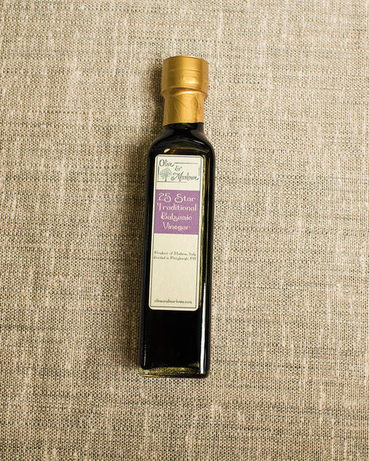 Bottle of balsamic vinegar with a gold cap on a textured beige background