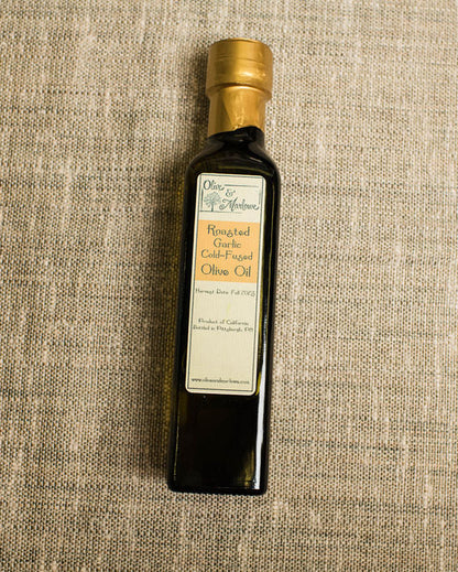 Bottle of olive oil with a gold cap on a textured beige background