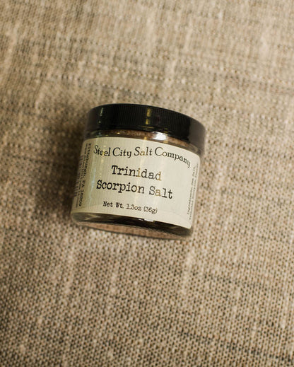 Small container of Trinidad Scorpion Salt on a textured beige surface