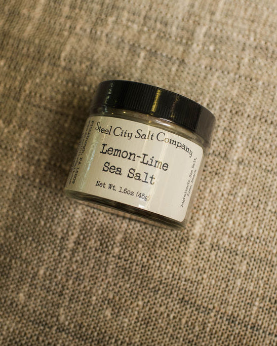 Jar of Lemon-Lime Sea Salt from Steel City Salt Company on a textured fabric background