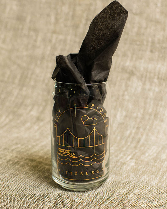 can shape Glass  with gold print pittsburgh art on a textured beige background