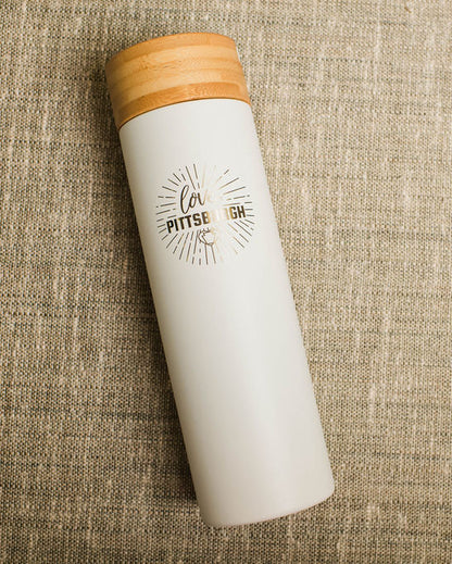 White tumbler with wooden lid on a textured beige surface