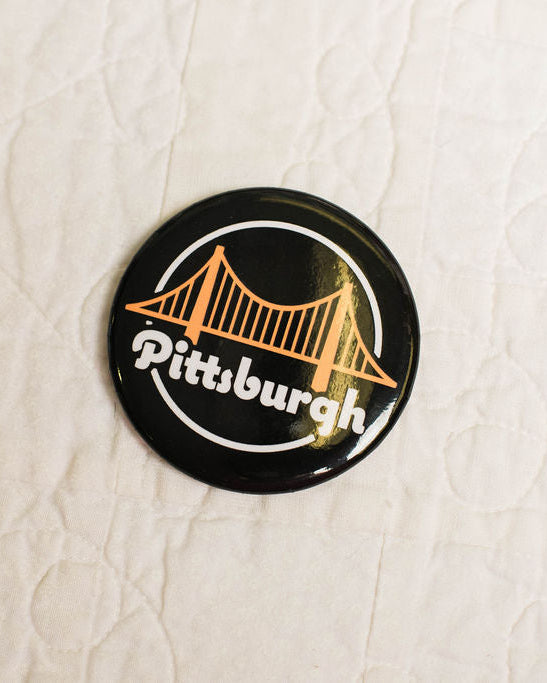 round magnet with Pittsburgh bridge design on a textured beige background