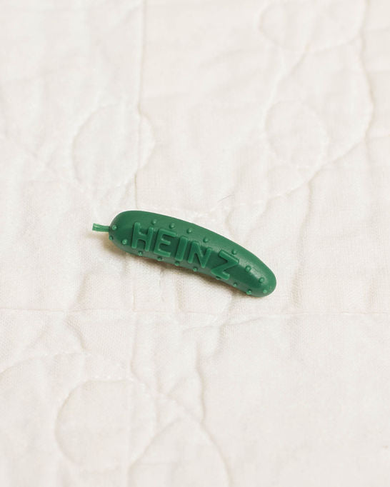 Green plastic pickle pin on a white textured background