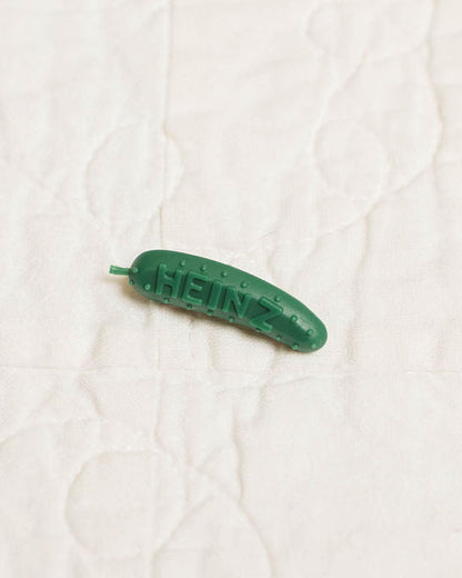 Green plastic pickle pin on a white textured background