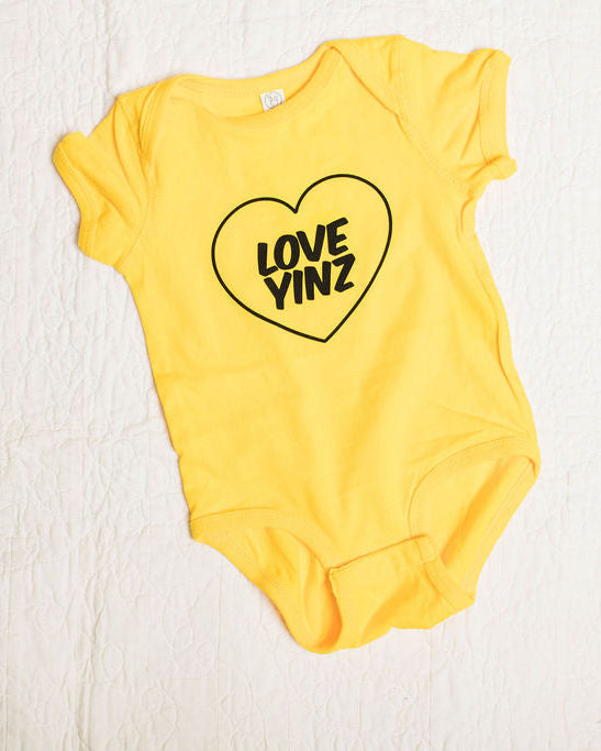 Yellow baby onesie with a heart-shaped  love yinz logo on a white background