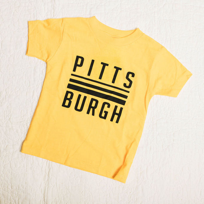 Yellow t-shirt with 'Pittsburgh' text on a light wooden surface
