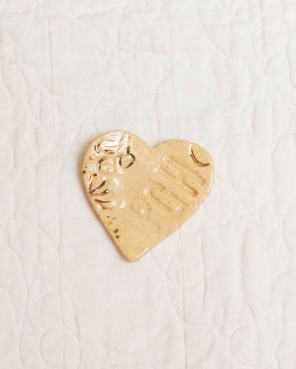 Gold accent heart-shaped trinket dish with PGH stamp on a textured white surface