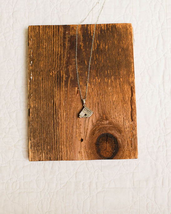 silver incline pendant necklace on wood background