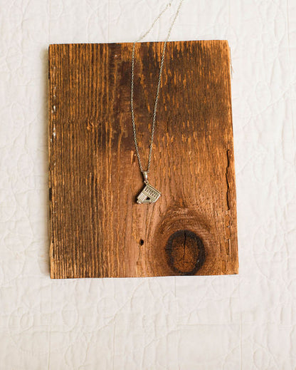 silver incline pendant necklace on wood background