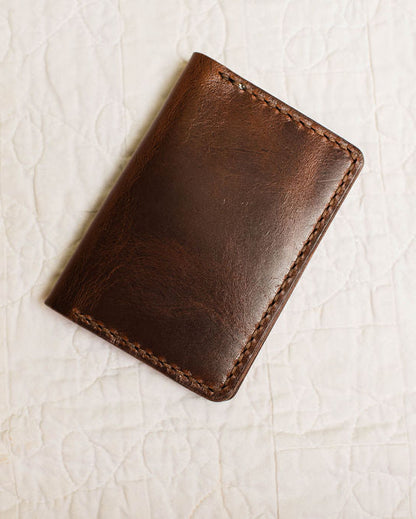 Brown leather wallet on a textured beige surface
