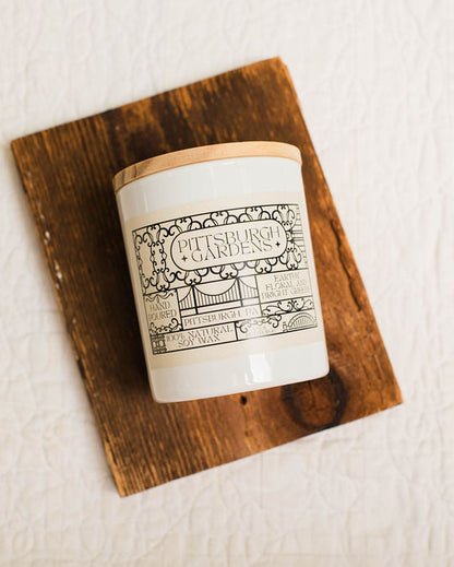 Candle with a decorative pittsburgh gardens label on a wooden coaster