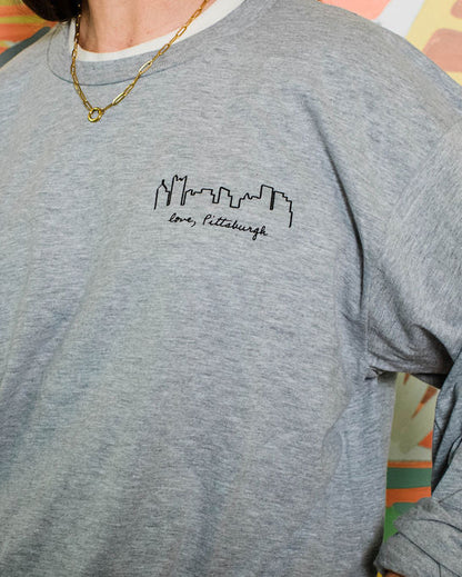 Person wearing a gray sweatshirt with a logo in front of a colorful abstract background