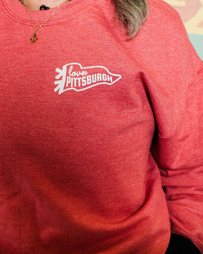 Person wearing a red sweatshirt with 'Love Pittsburgh' logo against a colorful abstract background