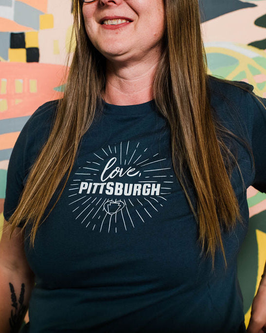 Person wearing a 'Love Pittsburgh' t-shirt in front of a colorful mural.