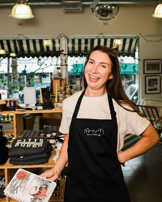 Woman wearing a black apron holding a menu in a restaurant setting