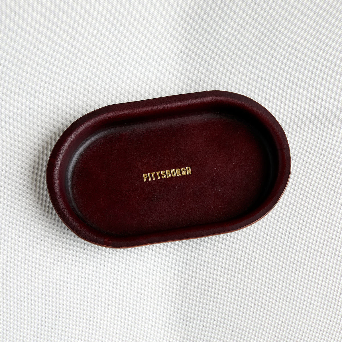 brown leather oval shape tray with embossed gold "pittsburgh"
