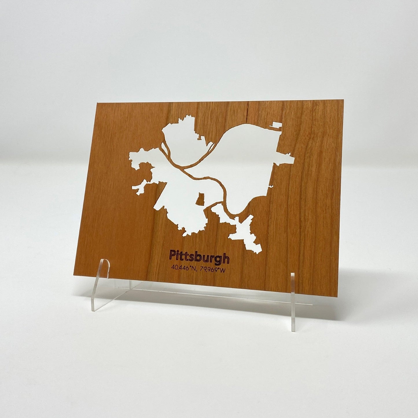 Wooden plaque with a white map of Pittsburgh on a white background