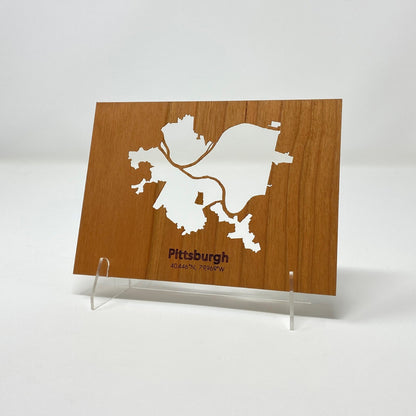 Wooden plaque with a white map of Pittsburgh on a white background